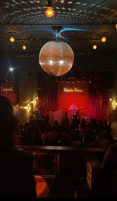 a group of people sitting in front of a stage with disco balls hanging from the ceiling