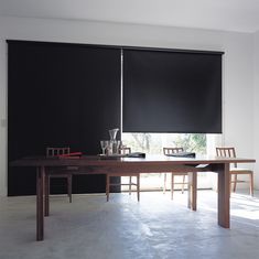 a dining room table with chairs and black roller shades