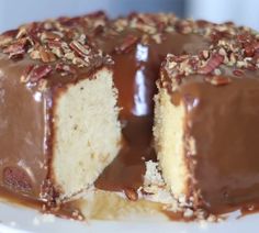 a cake with chocolate frosting and pecans on top is cut in half to show the inside