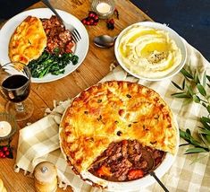 a table topped with lots of food next to wine glasses and plates filled with food