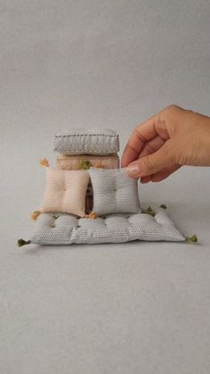 a hand is holding three pillows on top of each other