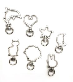 six metal clips with different shapes and sizes on white background, including one in the shape of a heart