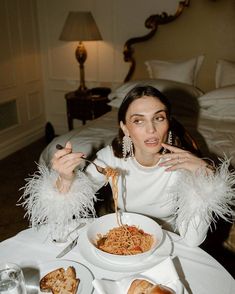 a woman sitting at a table with food in front of her and eating from a bowl