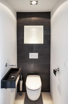 a white toilet sitting in a bathroom next to a black counter top sink and mirror