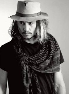 a man with long hair wearing a hat and scarf