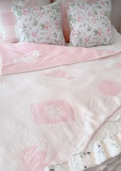 a bed with pink and white sheets, pillows and blankets on top of the bedspread