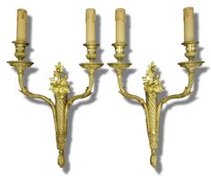 three golden wall sconces with candles on them