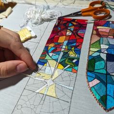 someone is working on stained glass designs with scissors and yarns in front of them