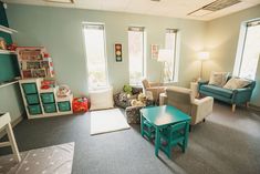 a living room filled with lots of furniture next to two windows and a blue coffee table