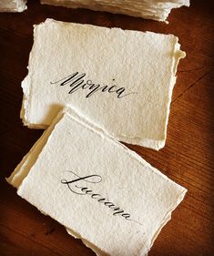 three pieces of paper with writing on them sitting on top of a wooden table next to each other