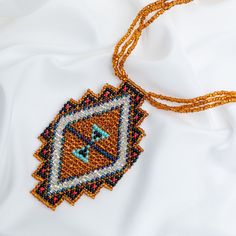 Trendy and tribal-inspired, the Mayan Pyramid Beaded Pendant Necklace makes a bold statement. Perfect for pairing with whites or denim for a great boho look. Made by women artisans of La Casa in Guatemala. Since 2000, La Casa Cotzal has designed a range of Guatemalan handcrafted pieces produced by artisan communities throughout the country. Mayan women traditionally have been backstrap loom weavers, but increasingly they are learning to use pedal looms as well. In traditional Guatemalan weaving, the two main specialized techniques are ikat and supplementary weft brocade. Artisans at La Casa are versed in both weaving techniques as well as in intricate bead work. The work provided by La Casa is vital to the women's families and communities. Glass beads & cotton thread Pendant: 3.25" H x 2" Artisan Beaded Jewelry For Festivals, Artisan Beaded Jewelry For Festival, Bohemian Orange Beaded Necklaces For Jewelry Making, Orange Bohemian Beaded Necklaces For Jewelry Making, Bohemian Orange Beads For Jewelry Making, Handmade Beaded Necklaces For Festivals, Bohemian Orange Beaded Chain Necklace, Bohemian Beaded Chain For Crafting, Bohemian Beaded Necklaces For Festivals As Gift