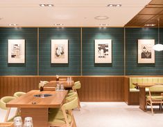 an empty restaurant with green walls and wooden tables in the foreground, along with yellow upholstered chairs