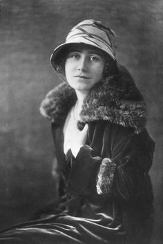 an old black and white photo of a woman wearing a hat with fur on it