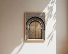 an arched doorway in a white wall with sunlight coming through the window