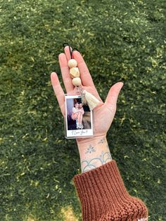 a person's hand holding up a small photo frame with a tassel on it