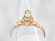 The warm glow of this antique gold is a lovely compliment to the brilliant green emeralds set on each side of the beautiful old mine-cut diamond! The details of the tiny prongs that surround each of these stones bring beauty and intricacy to this antique ring. Metal: 14K Antique Rose GoldGem: Old Mine Cut Diamond .11 CaratsGem Measurements: 2.4 mm, Round Accents: 2 Emeralds Ring Size: 5.50 Vintage Green Emerald Ring With Rose Cut Diamonds, Green Emerald Cut Diamond Ring With Rose Cut Diamonds, Green Emerald Cluster Ring With Rose Cut Diamonds, Art Deco Green Emerald Ring With Rose Cut Diamonds, Antique Green Oval Diamond Ring, Antique Green Diamond Ring With Center Stone, Art Deco Emerald Ring With Rose Cut Diamonds, Vintage Green Diamond Ring With Center Stone, Green Emerald Ring With Rose Cut Diamonds For Anniversary