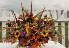 a vase filled with lots of different types of flowers on top of a white table