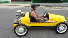 a man driving a yellow pedal car down the street