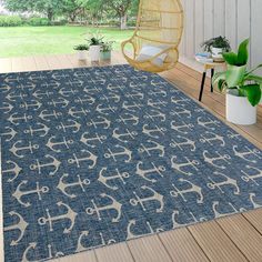 a large blue rug on a wooden deck with a chair and potted plant in the background