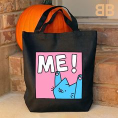 a black tote bag with a blue cat on it and the words me in pink