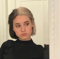 a woman with blonde hair is looking at her reflection in the mirror while wearing a black top