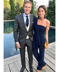 a man in a suit and tie standing next to a woman wearing a blue dress