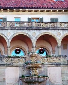 an ornate fountain with wreaths on it in front of a large white and red building