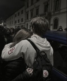 two people standing next to each other in front of a car