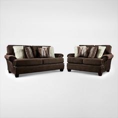 two brown couches sitting next to each other with pillows on them and one chair