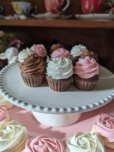 several cupcakes are arranged on a cake plate with pink and white frosting