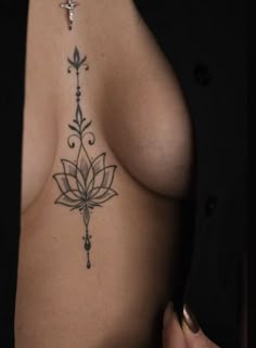 a woman's breast with a tattoo design on her left side and cross in the middle