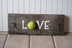 a tennis ball sitting on top of a wooden sign with the word love painted on it