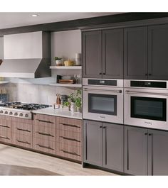 a kitchen with gray cabinets and stainless steel appliances, including an oven, range hood, microwave, dishwasher, and sink