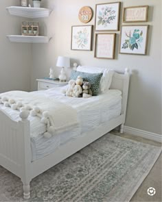 a white bed sitting in a bedroom next to two pictures on the wall above it