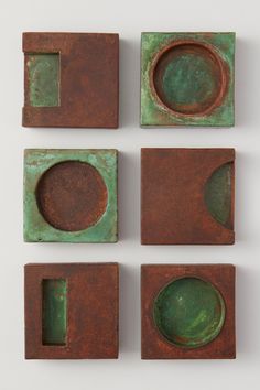 four pieces of metal with green pattered paint and square holes in them, all on top of each other