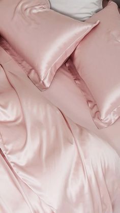 an unmade bed with pink sheets and pillows on top of it, next to a pillow case