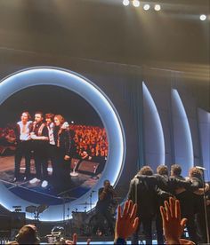 a group of people standing on top of a stage with their hands in the air