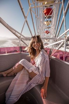 a woman sitting on the edge of a ferris wheel looking at the camera and smiling