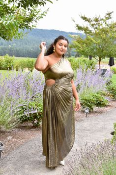 We're crowning the Olympia Pleated One Shoulder Gown the dress of the year! In a luxe shimmering gold metallic, this pleated plus size midi dress features fluid draping, a one shoulder silhouette and an elasticized keyhole cutout that helps flatter all different body types. Asymmetrical hem. Hidden side zip. Available in gold metallic and pearl. Glamorous Gold One-shoulder Dress For Gala, Glamorous Gold One-shoulder Dress For Formal Events, One-shoulder Metallic Dress For Parties, Glamorous Gold One-shoulder Formal Dress, Gold One-shoulder Maxi Dress, Elegant One-shoulder Metallic Dress, Mettalic Pleated Dress, Glamorous Gold One-shoulder Dress With Asymmetrical Neckline, Luxury Pleated One-shoulder Maxi Dress