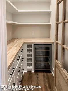 an empty walk in pantry with white cabinets and wood flooring is seen from the doorway