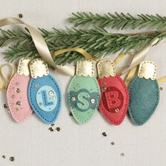 three christmas ornament hanging on a tree branch with ribbons and decorations around it