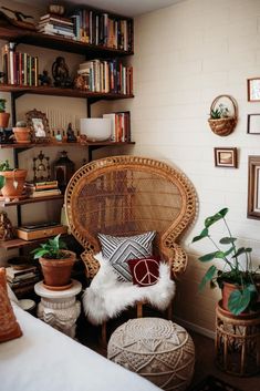 a wicker chair and ottoman in a room with bookshelves, potted plants, and other decorative items