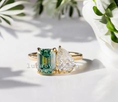 three different colored stones on top of each other in gold and silver ring settings with flowers behind them