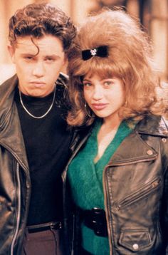 two people standing next to each other wearing black leather jackets