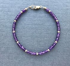 "Amethyst Bracelet Sparkling purple and gold....what's not to like? Genuine amethyst rondelles encircle this bracelet, which is interspersed with 14K gold filled beads. Lobster clasp closure with pretty rope detail ring at clasp. Fashioned on professional quality beading wire for strength and flexibility. A nice addition to your collection. You know -- the one that keeps growing. Unashamedly. Bracelet collectors unite! Faceted rondelles of genuine amethyst, about 3.5-4mm All components 14K gold Purple Rondelle Beaded Bracelets As Gift, Purple Rondelle Amethyst Bracelets, Purple Amethyst Rondelle Bracelets, Purple Rondelle Beaded Gemstone Bracelets, Amethyst Beaded Bracelets With Spacer Beads As Gift, Amethyst Beaded Bracelets With Faceted Beads, Purple Spiritual Bracelets With Faceted Beads, Adjustable Amethyst Rondelle Beaded Bracelets, Purple Spiritual Bracelet With Spacer Beads