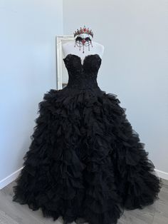 a black dress is displayed on a mannequin headdress in front of a white frame