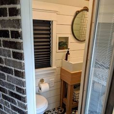 a bathroom with a toilet, sink and brick wall