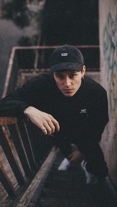 a young man sitting on top of a wooden bench