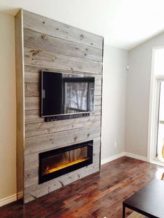 a living room with a tv mounted on the wall and wood flooring in front of it