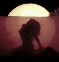 the silhouette of a woman in front of a full moon with her hair blowing back